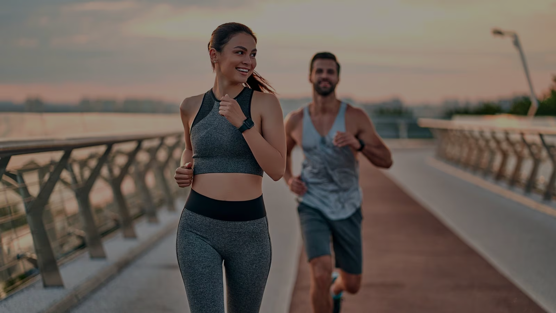 Fitness apparel couple running on a bridge during sunset.