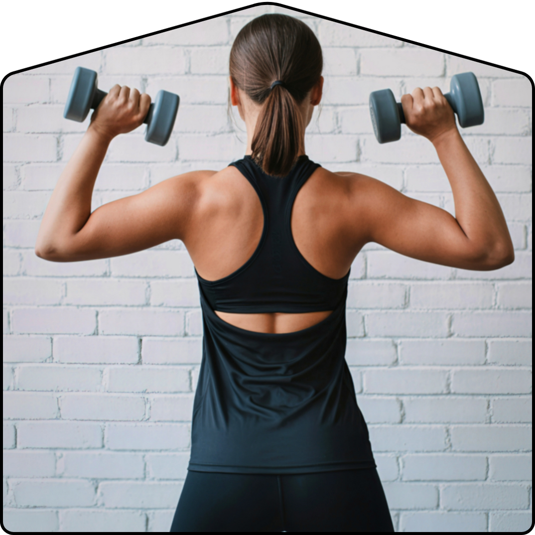 Person lifting dumbbells in front of a white brick wall