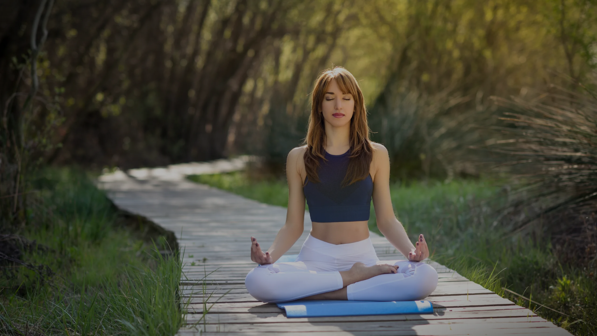 Woman practicing yoga on a wooden path in a natural setting